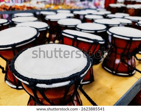 Rows of mini Kendang musical instruments neatly arranged on the table. This musical instrument has a white drum surface and a brown wooden body tied with black rope.