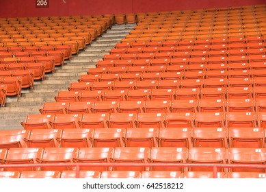 Rows Of Multilevel Empty Orange Metal Grandstand Seats With Number At An Indoor Sport Stadium In Texas, America. Seamless Pattern Of Stadium/arena Chairs On Main Stand For Sport Concept Background.