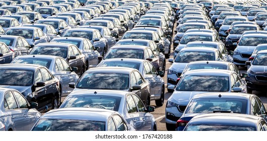 Rows of a new cars parked in a distribution center on a car factory on a sunny day. Parking in the open air. - Shutterstock ID 1767420188