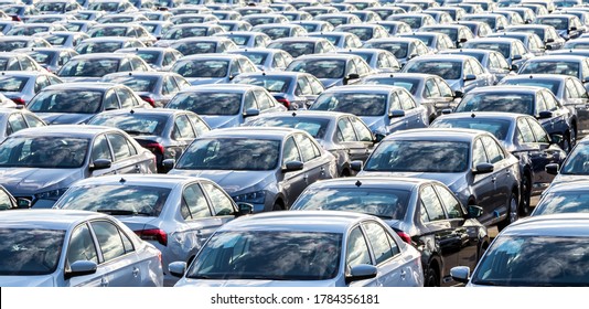 Rows of a new cars parked in a distribution center on a car factory on a sunny day. Top view to the parking in the open air. - Shutterstock ID 1784356181