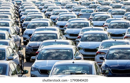 Rows of a new cars parked in a distribution center on a car factory on a sunny day. Top view to the parking in the open air. - Shutterstock ID 1790840420