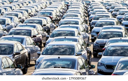 Rows of a new cars parked in a distribution center on a car factory on a sunny day. Top view to the parking in the open air. - Shutterstock ID 1795089367