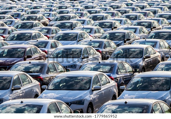 Rows
of a new cars parked in a distribution center on a car factory on a
sunny day. Top view to the parking in the open
air.