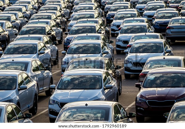 Rows\
of a new cars parked in a distribution center on a car factory on a\
sunny day. Top view to the parking in the open\
air.