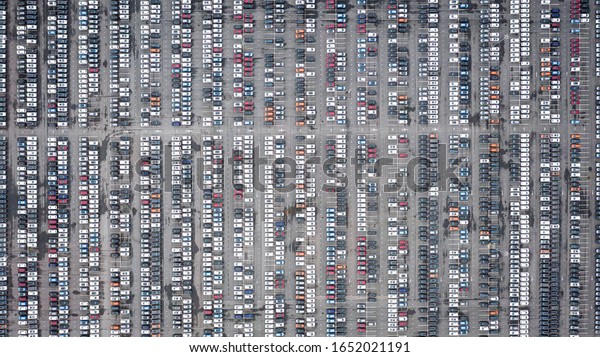 Rows of new cars in the\
parking lot. Aerial view of large parking lot full of cars of\
various colors