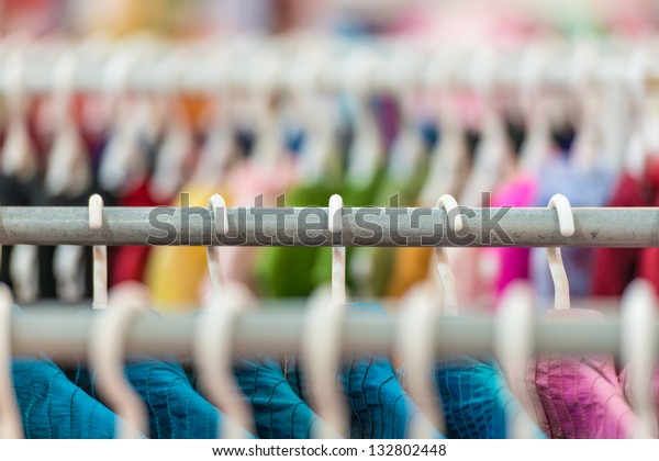 Rows of new colorful clothing on hangers at
shop in foreground and background. Great choice of casual clothes
of different colors. Apparel ready for sale. Going shopping. Trade
and commerce.