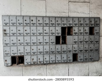 Rows of old abandoned mailboxes attached to the wall of a vacant residential building. Concept of urban decay, neglected property, aging infrastructure, abandoned housing, and forgotten places