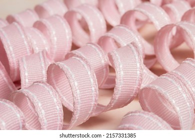 Rows Of Pastel Pink Ribbon Spiral Curls At An Angle On A Pale Pink Marble Surface. Closeup, Shallow Depth Of Field.