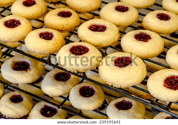 Rows of raspberry thumbprint cookies
cooling on wire baking rack sitting on counter
top