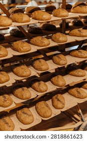Rows of raw artisan bread dough loaves proofing on multi-tier bakery racks before baking, showcasing traditional bread preparation, fermentation, and commercial bakery production