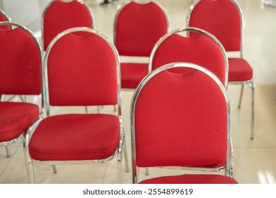 Rows of red chairs with metallic frames arranged neatly indoors, showcasing a clean, organized, and modern seating design suitable for events, conferences, or gatherings