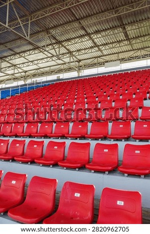 Rows of red stadium seats form a vertical pattern beneath covered stands.