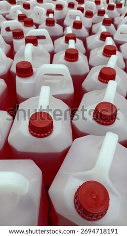 Rows of red-capped plastic jugs with handles, suitable for industrial storage background. Mobile photo
