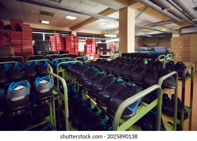 Rows Of Shelves Full Of New Modern Running Shoes And Sneakers Standing In Big Warehouse Premise In Shop Or Footwear Making Factory. Sports Shoe Manufacturing Industry, Production And Storage Concept