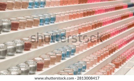 Rows of small glass jars filled with colorful cosmetic pigments and powders displayed on tiered white shelves in a beauty store