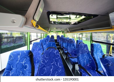 Rows Of Soft Blue Seats Inside Saloon Of Empty City Bus With Skylight.