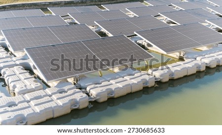 Rows of solar panels are mounted on buoyant platforms creating a large solar power plant on the surface of a lake or reservoir