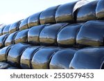 Rows of stacked silage bales wrapped in black plastic