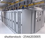 Rows of tall, gray server cabinets line a clean data center floor. Overhead cabling and infrastructure are visible. The cabinets have perforated doors.