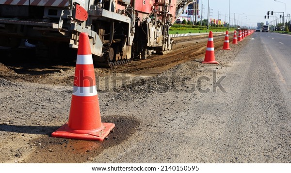 Rows of traffic cones on the road. Red and white\
plastic cones or temporary traffic control devices for warning to\
avoid sections of the road under repair. Selective focus on\
subjects closely