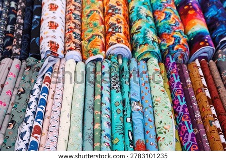 Rows of vibrant patterned fabric rolls on display, offering a wide selection of textiles for crafting