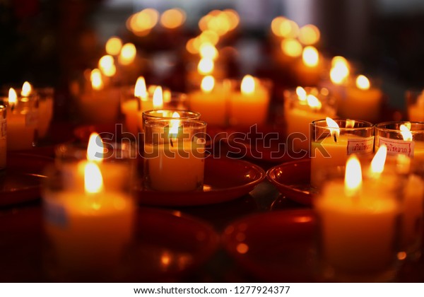Rows of Votive Candles in Glass, Sacrifices for\
the Gods, Blurred of candles, Red Candle is kindle a fire in glass,\
Abstract Meaning of\
Religions