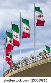 Rows of waving Iranian flags on a street bridge in Tehran against Cloudy Blue Sky.