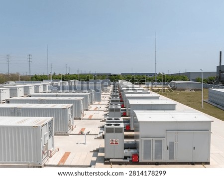 Rows of white containerized energy storage battery systems in an outdoor industrial power facility