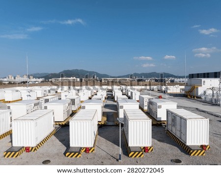 Rows of white containerized energy storage systems arranged outdoors under blue sky