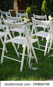Rows of white folding chairs lawn before wedding ceremony