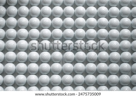 Rows of white golf balls, the ball in the middle has a res heart shape printed on it.