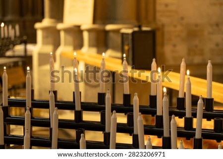 Rows of white prayer candles burning inside historic church.