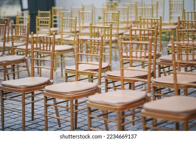 ROWS OF WOODEN COLOR CHAIRS WITH NO ONE SITTING ON THEM 