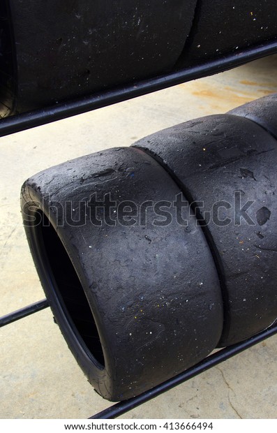 Rows of worn out slick tires in a pit box of a\
racing circuit