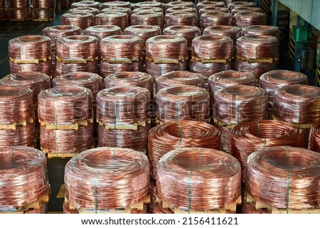 Rows of wrapped copper cable coils in light plant warehouse