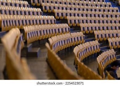 Rows of yellow seats of a rounded empty stadium