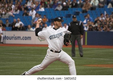 Roy Halladay Delivers A Pitch, With Umpire In Background