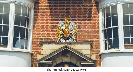 Royal Arms Of England Above Door Pediment, Coat Of Arms Between Windows Against Red Brick Wall