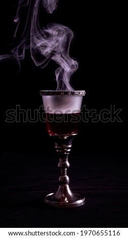 Royal glass with precious stones, red dry wine and magical smoke. Reminiscent of ancient kings, witch poisons and castles.