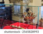 Royal gold crown and scepter display in glass case at historical museum exhibition.