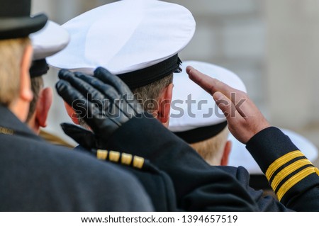 Royal Navy officers salute during Remembrance Day commemorations.