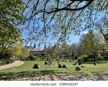 The Royal Pavilion And Gardens, Brighton, East Sussex, England, UK. Spring 2022. Historic And Magnificent Landscaped Organic Gardens. View Through Trees, Leaves And Bushes. People Sun Bathing.