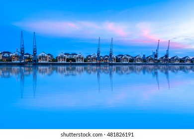 Royal Victoria Dock In London At Sunset With Dockside Cranes And Waterfront Terraced Houses