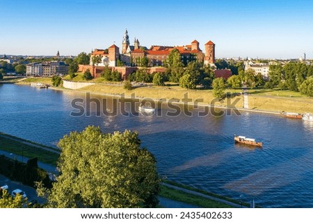 Royal Wawel Cathedral and castle in Krakow, Poland. Aerial view in sunset light. Vistula River, tourist boats, riverbanks with parks, trees. promenade and  walking people
