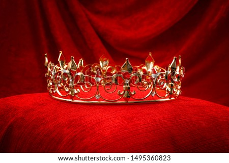 Royalty, monarch coronation or leadership conceptual idea with king gold crown with jewels on red velvet pillow