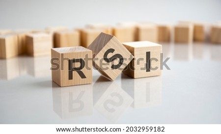 RSI - Relative Strength Index acronym concept on cubes, gray background. Reflection on the mirrored surface of the table. Selective focus.