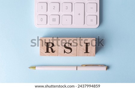 RSI word on a wooden block with pen and calculator on blue background . 