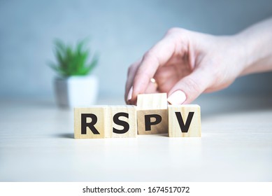 rsvp acronym request for a response from the invited person on wooden cubes with female hand.