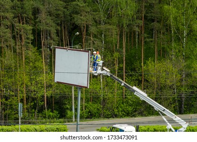 RU, Moscow, 13.05.2020: Two Men In A Lift Basket Change Image On A Billboard Near A Road