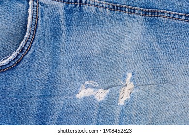 Rubbed pocket and other places on a blue jeans. Texture of the old torn denim showing the frayed threads, fragment 